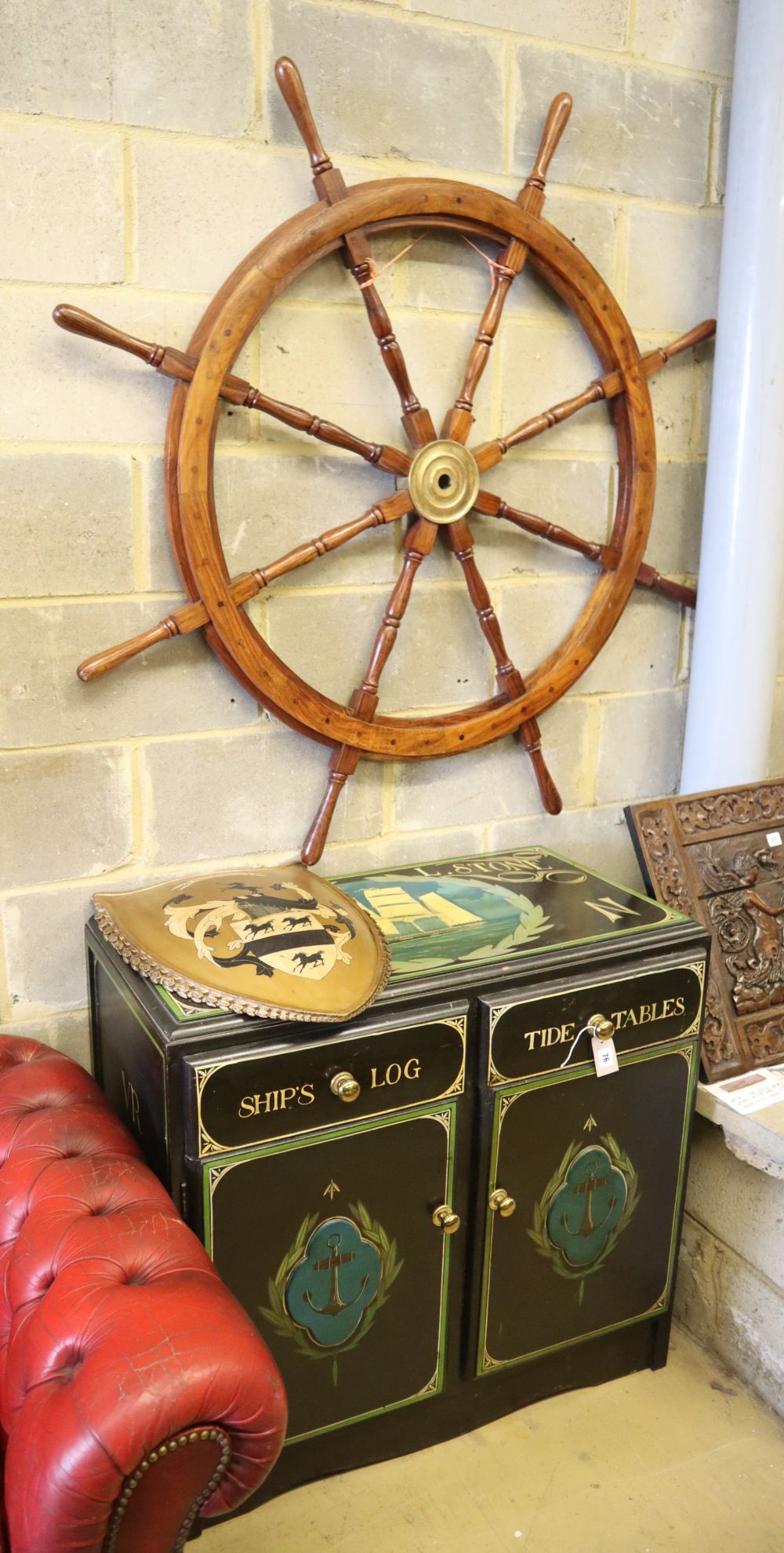 A painted nautical themed side cabinet, together with a heraldic shield and ships wheel, cabinet W.92cm, D.47cm, H.86cm